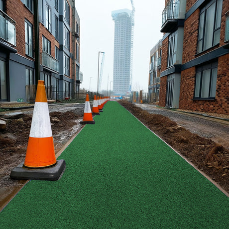 Green spaghetti mat pathway with orange traffic cones in an urban setting