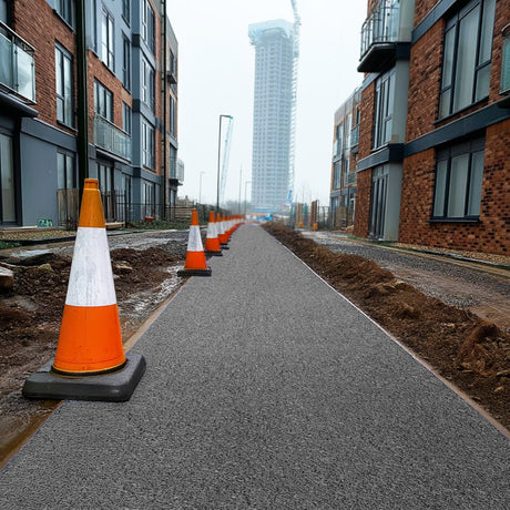 Construction cones on a grey walkway site mat with modern buildings in the background.