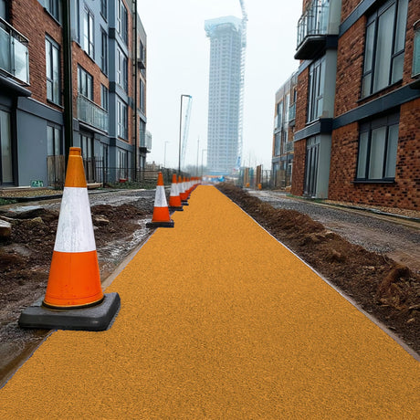 Orange traffic cones on a orange walkway site mat with residential buildings in the background